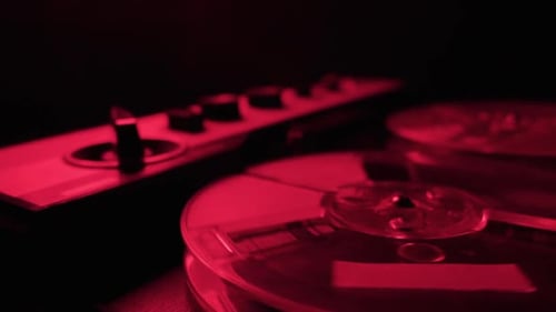 Vintage Reel to Reel Tape Recorder Playing Under Dark Red Lighting