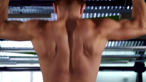 Kaukasischer Mann führt im Fitnessstudio intensive Klimmzüge durch