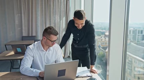 Men Collaborating on Laptop in Modern Office