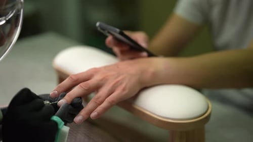 Manicurist Working on Client With Smartphone