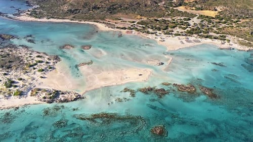 Vue aérienne par drone d'un lagon turquoise avec des bancs de sable et des parasols en paille le long de la plage, Elafoniss