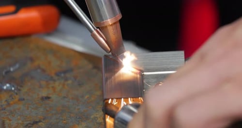 Laser welding machine with hand hold gun. Laser welding is shown in close-up.