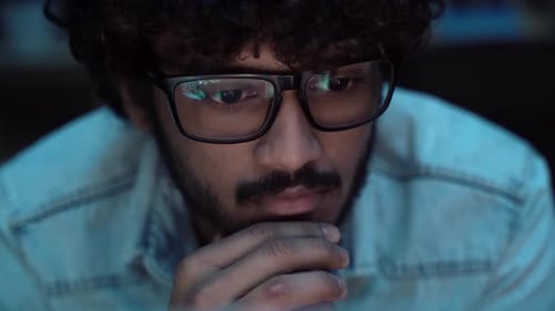 Man in Glasses Looking at Computer Screen at Night