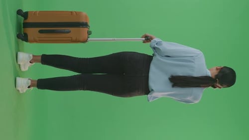 Back View Asian Woman Traveler With Luggage Talking On Smartphone While Standing In The Green Screen