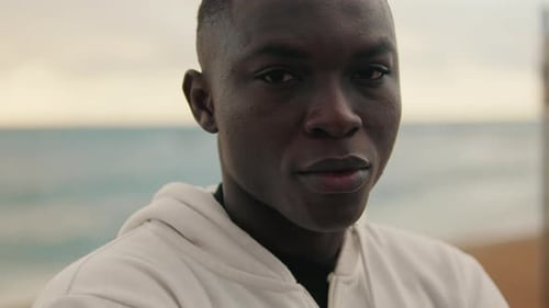 Close-up of young man against the sea stands with his arms crossed on his chest