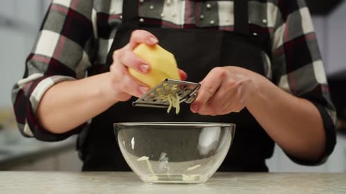 Woman Grating Potato into Bowl in Bright Kitchen