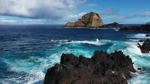 Majestic Ocean Waves Crashing Against Dramatic Volcanic Rock Island Coastline
