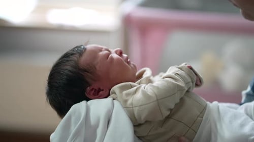 Close-up of a newborn baby crying, lying on a soft blanket in a peaceful home environment,
