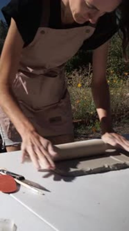Woman Using Rolling Pin on Clay Slab Outdoors