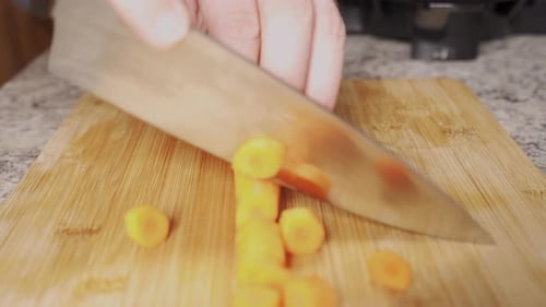 Carrot Slices Being Chopped on Wood Cutting Board