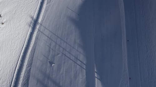 Aerial birds eye shot following skier on snowy white slope in alp mountains