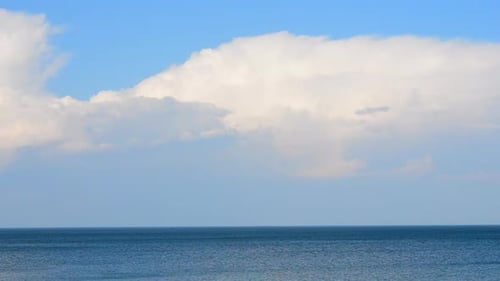 Movement Large White Cumulus Rain Clouds in Blue Sky Over Blue Sea on Sunny Day