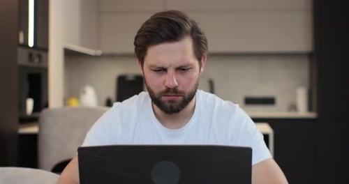Man Works on Laptop, Touches Temples