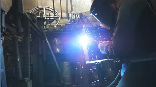 Welder Works on Metal in Industrial Workshop