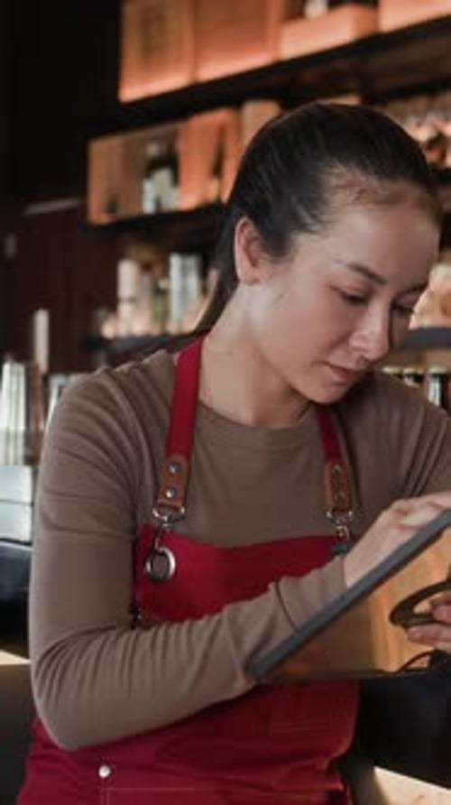 Vertical of Waitress Using Digital Tablet while Working in Restaurant
