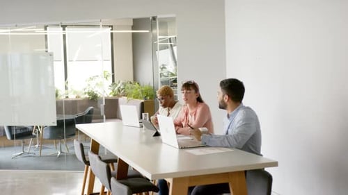 Collaborating in modern office, multiracial colleagues using laptops, discussing project ideas