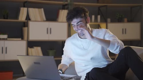 Young Man Laughing Using Laptop at Night