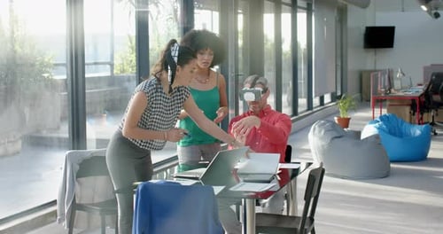 Caucasian businessman wearing vr headset while colleagues watching him at office