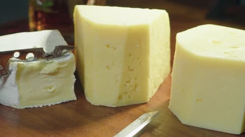 Cheeses on charcuterie board: Small knife cuts slice of Brie cheese