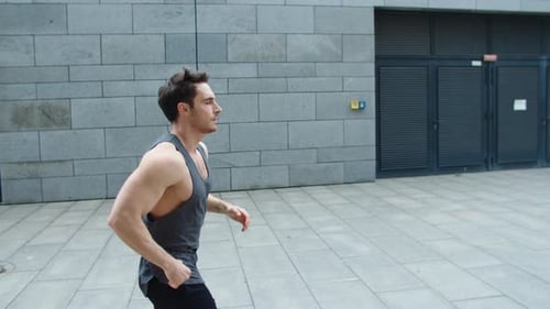 Fit young man running a training run exercise on urban city street in slow motion