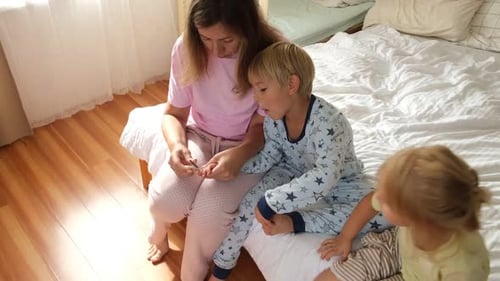 Mother Checks Temperature of Son at Home with Daughter