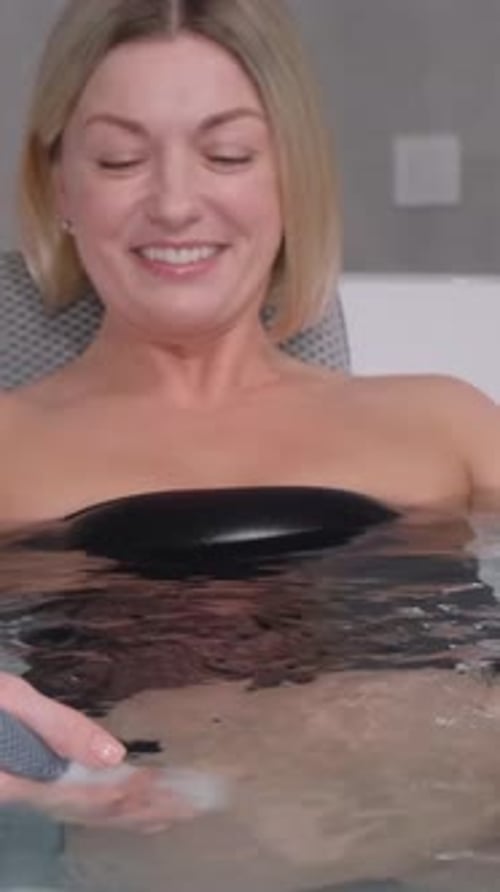 Vídeo vertical de um médico profissional dá uma hidromassagem a uma mulher