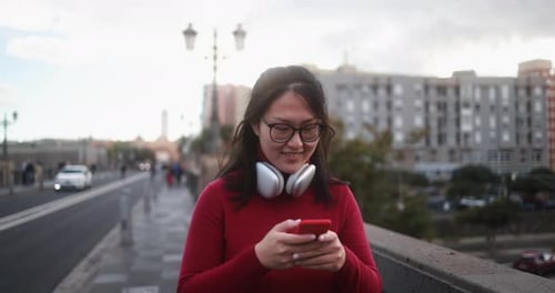 Young asian woman using mobile phone outdoor - City lifestyle concept