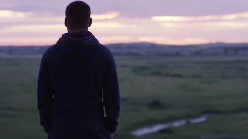 Young Adult Overlooking Rural Landscape During Sunset