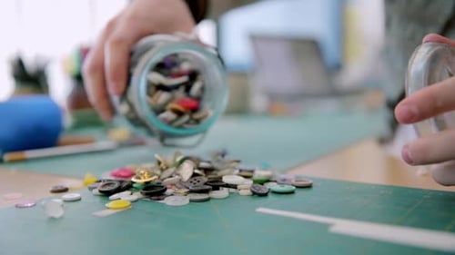 Craftswoman emptying jar of buttons on cutting mat in calgary alberta Canada