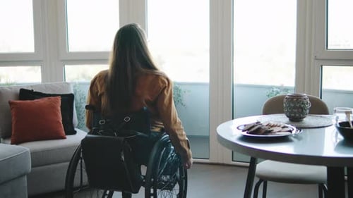 Woman in Wheelchair by Window in Modern Apartment
