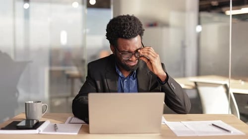 Stressed Businessman Suffering From Headache Working on Laptop at Office