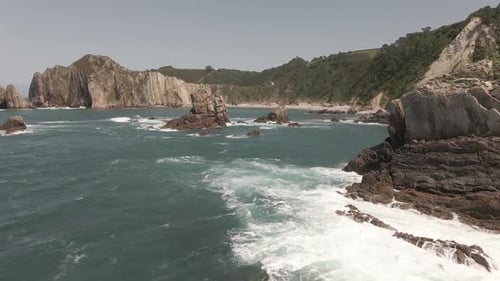 Distant View of a Beach Between Green Mountains with Rocks in the Water