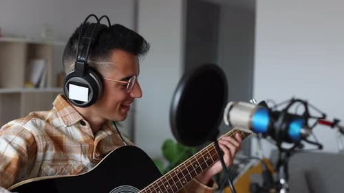 Young Man Playing Guitar and Singing at Home