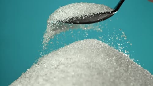 Sugar Pours Out of a Spoon on a Blue Background Filmed on a Highspeed Camera at 1000 Fps
