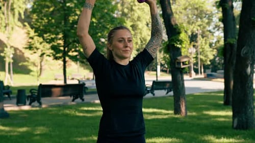 Athletic Woman Working Out with Dumbbells in Park