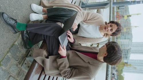 Two Coworkers Discussing Business Plan on Laptop on Riverside
