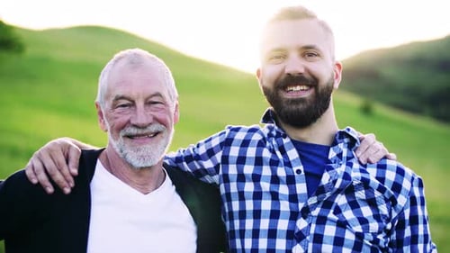 Smiling Senior Man with Adult Son in Nature