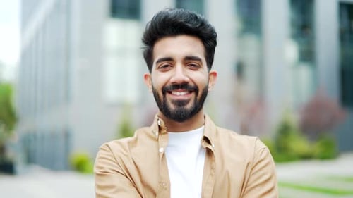 Close up. Portrait of a young bearded man smiling and looking at the camera. Handsome positive male