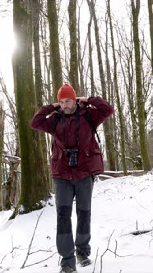 Abenteuerlustiger Fotograf, der durch einen verschneiten Winterwald geht