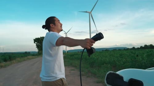 Progressive Man with His EV Car and Wind Turbine As Concept of Renewable Energy