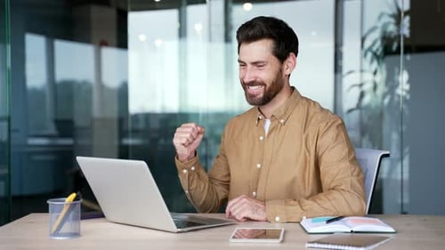 Man Working on Laptop Celebrating Success in Office