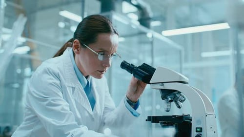 Female Scientist Using Microscope in Bright Laboratory Setting