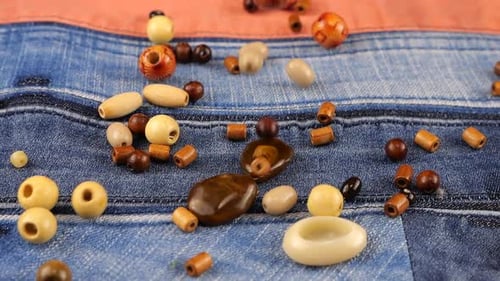 Wooden Beads Falling on Denim Background