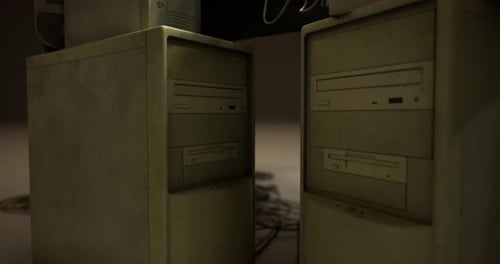Computadores em uma sala mal iluminada mostrando desgaste e idade devido ao uso prolongado