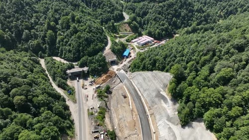 Aerial view of cranes and bridge foundation pillars on construction site of new highway road project