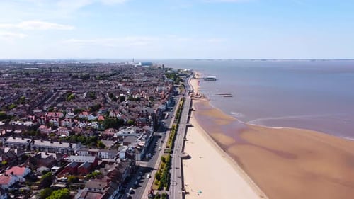 Aerial view heading along Grimsby Cleethorpes seaside town coastline towards holiday pier landmark