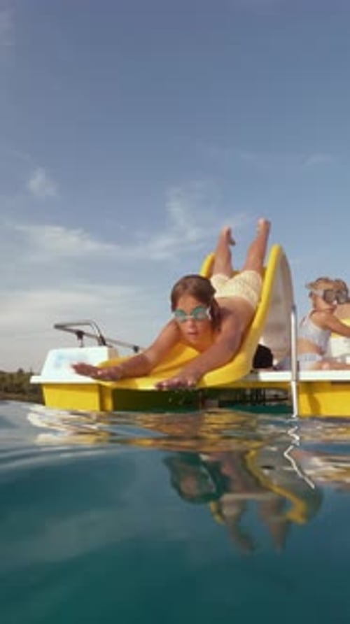 Vertical Video of Teenage Boy Sliding on Water Slide Into Sea