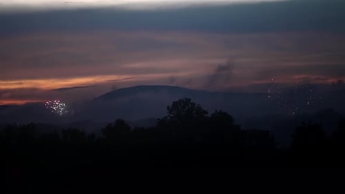 Uma fumaça fina sobe no ar quando a antena de fogos de artifício explode no céu com cores cintilantes e cintilantes