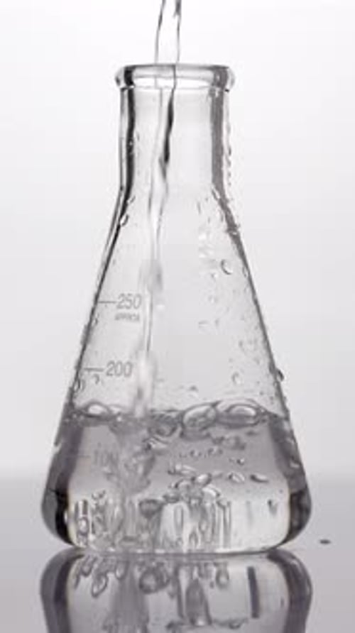 Chemisches Laborexperiment — Klare Flüssigkeit in eine Flasche gießen