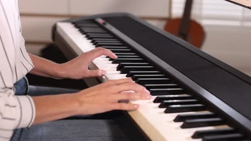 Woman playing synthesizer at home, closeup view